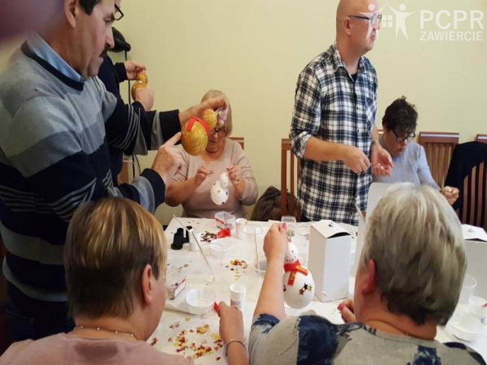 Zdjęcie: Grupa kobiet i mężczyzn przy stole maluje bombki w kształcie bałwanka
